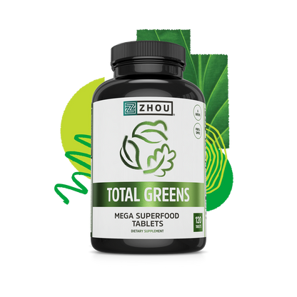 A bottle of Zhou Nutrition Total Greens, a spirulina supplement, with leafy label and green background.